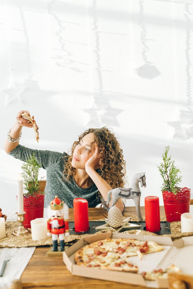 woman eating pizza on christmas decorated table