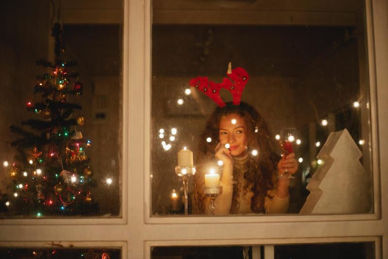 woman drinking wine in window reflection on Christmas