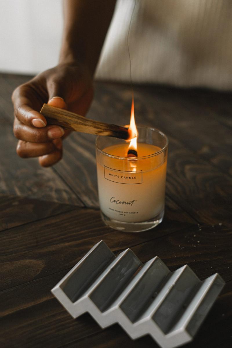 candle on wooden table being lit with sage