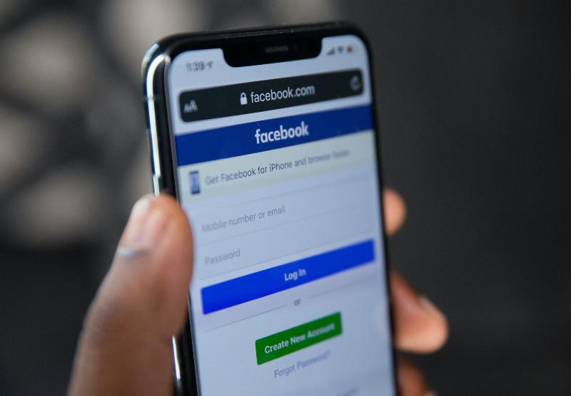 Facebook login page held by hand on a phone
