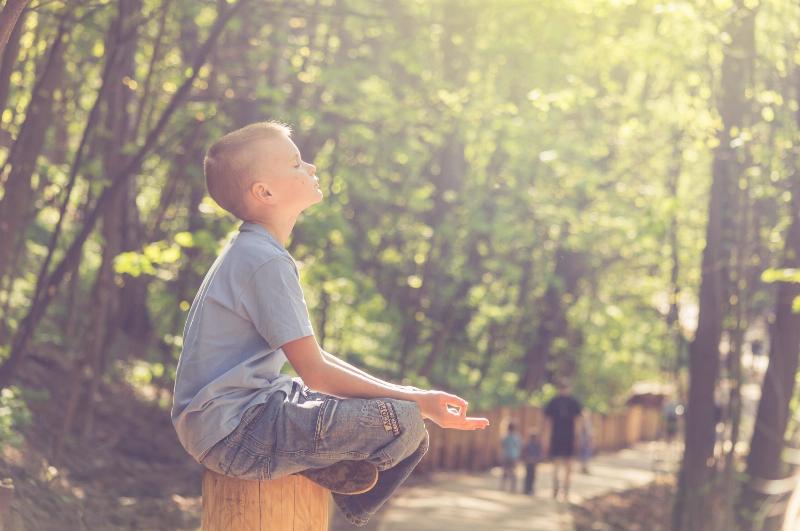 young boy meditating in the park