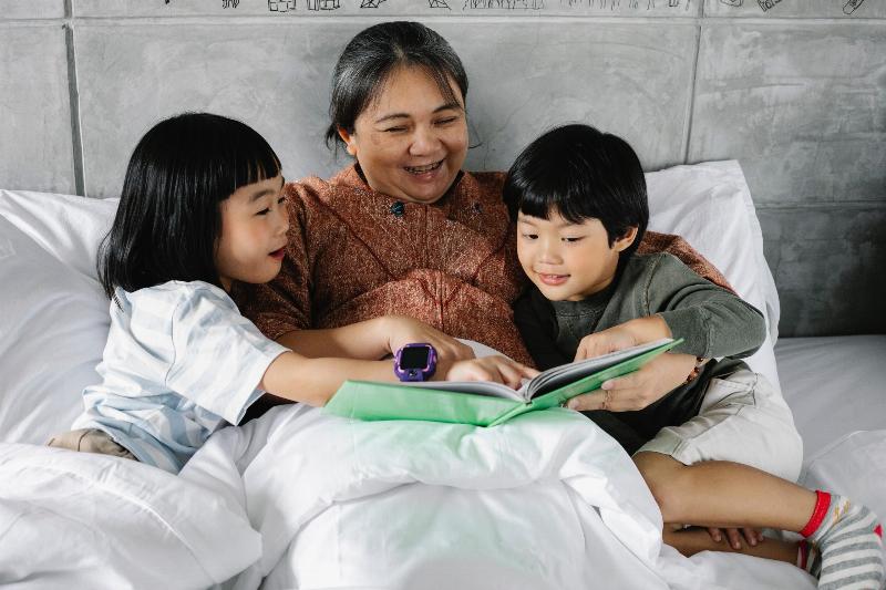 grandma reads story in bed to two children by her side