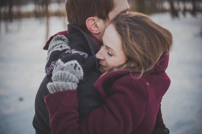 man and woman hug in the snow tightly