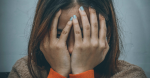 young woman hides her face with her hands
