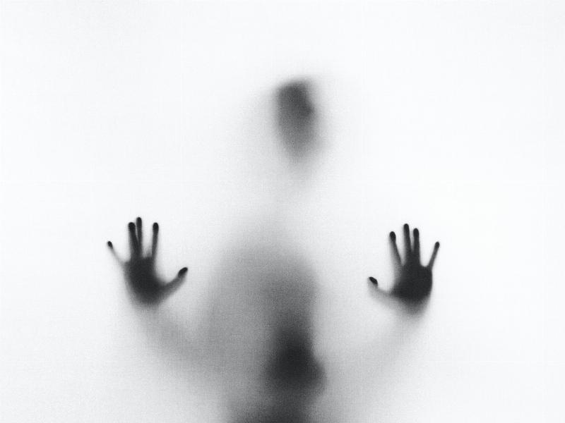 ghostly figure puts up hand against wall