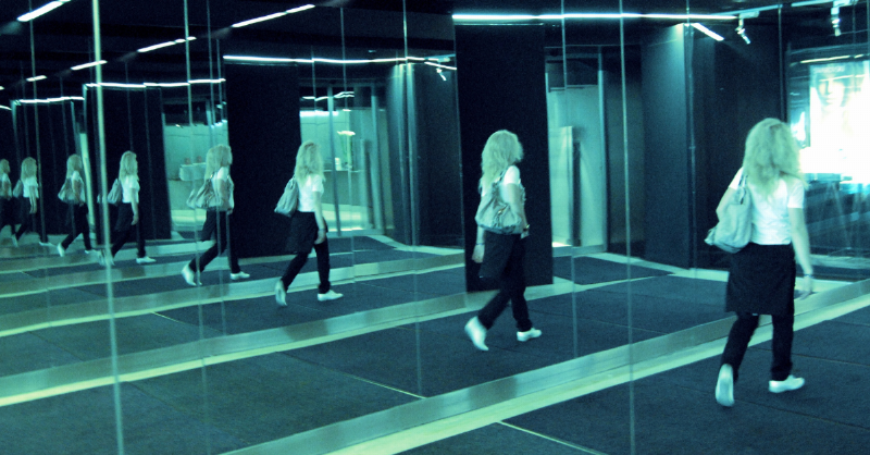 woman reflection as she walks past infinite mirror