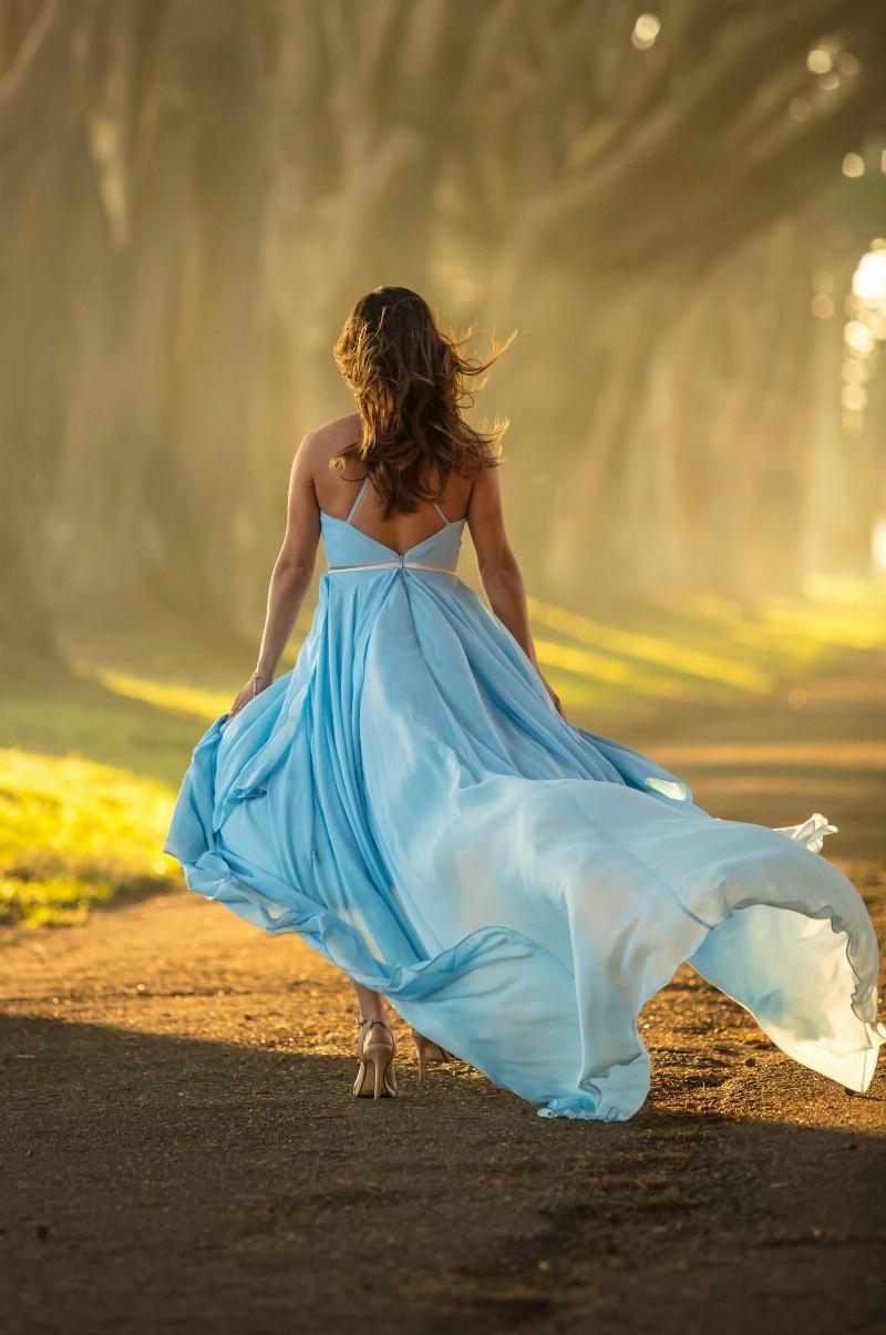 woman with blue dress walking in forest path