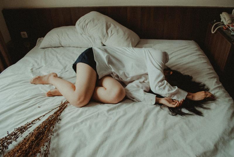 woman lays in bed with her hair covering her face