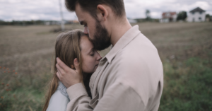 man kissing woma's forehead in a field