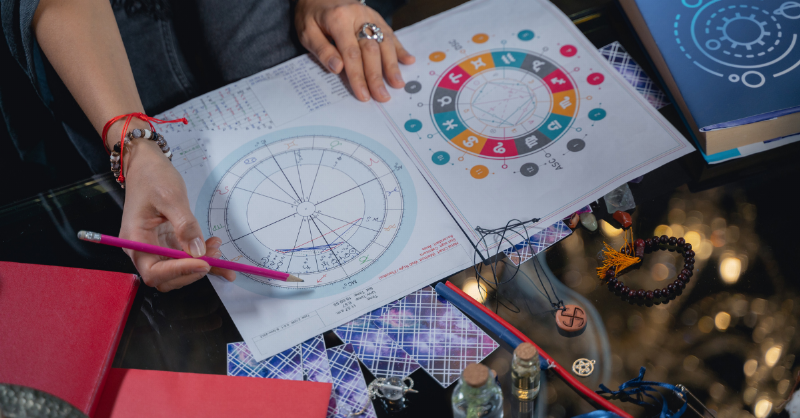 woman using pencil to draw on astrological chart