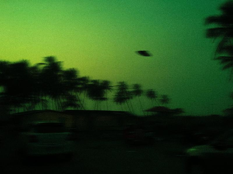 green sky with blurry ufo flying over parking lot