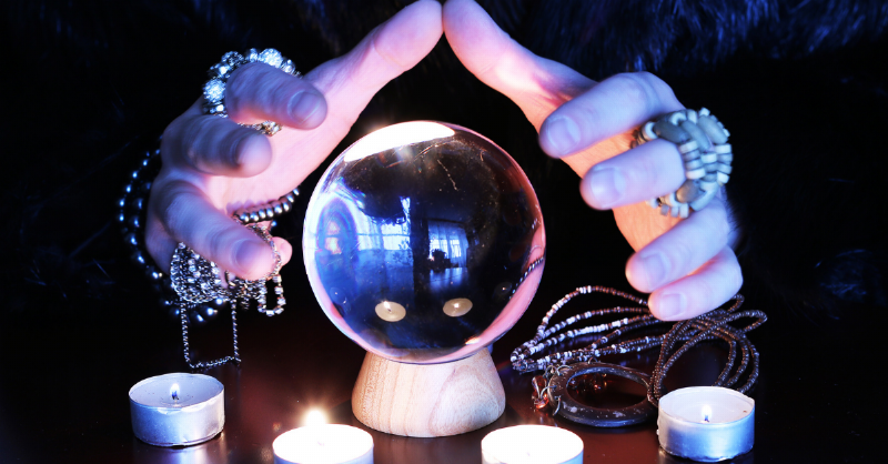 fortune teller puts hands around crystal ball and candles