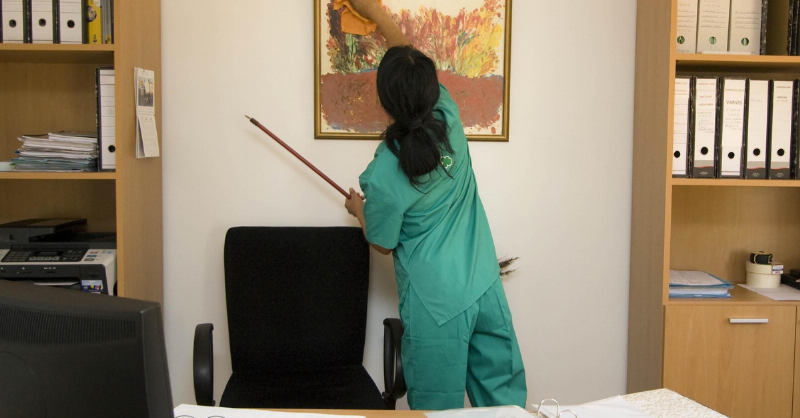 woman cleaning painting in green uniform