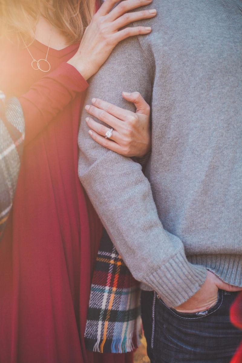 woman wraps her arm around a man's with engagement ring