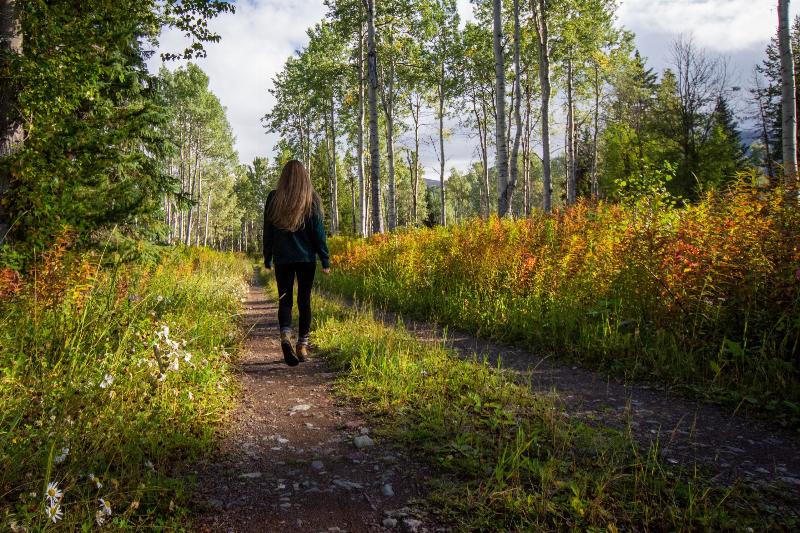 woman walks through a forest path