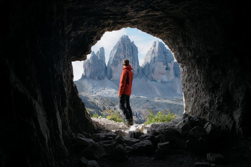 man stands at the entrance of a cave facing outwards