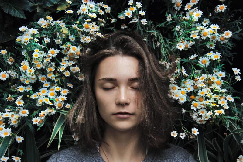 woman laying in a bed of flowers with eyes closed