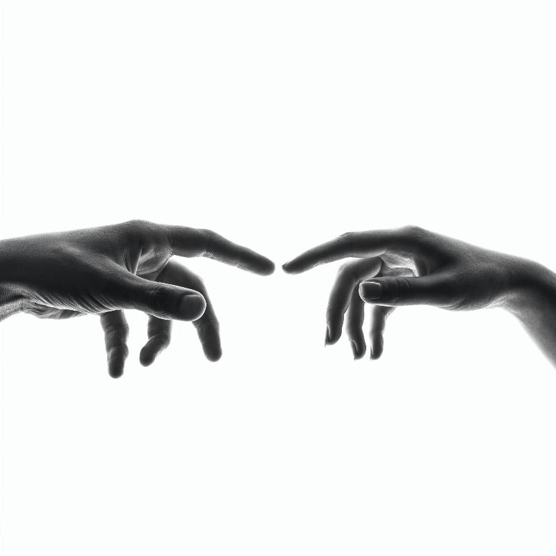 black and white photo of hand touching its reflection