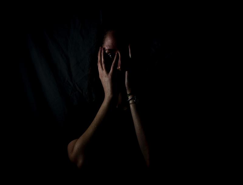 woman hides her face in darkess