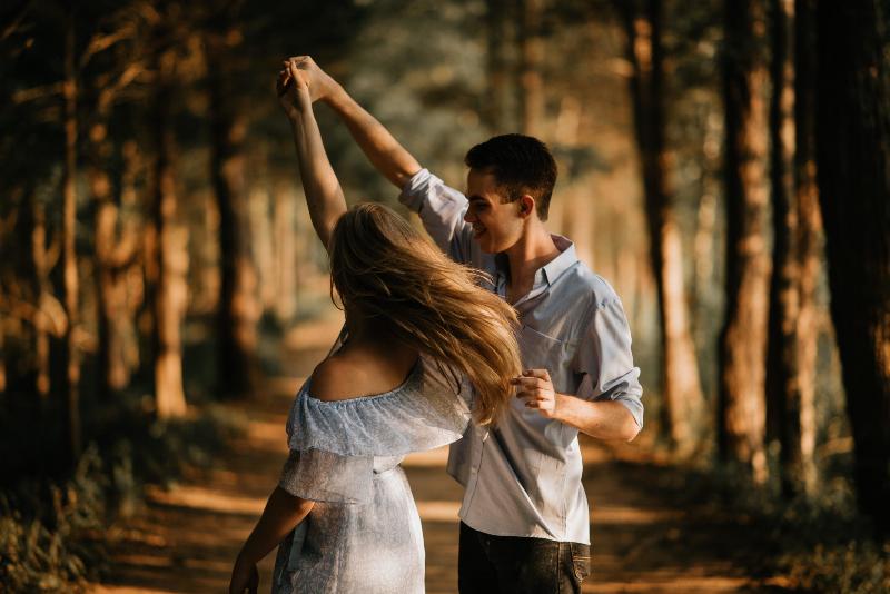 man spins woman around in forest
