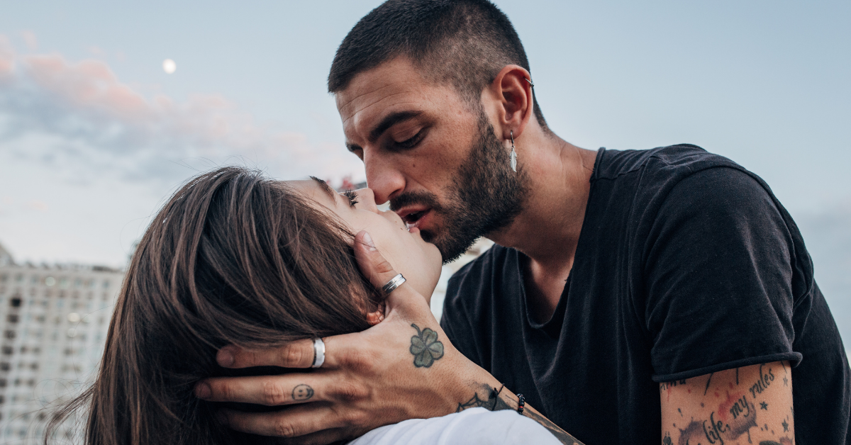 man leans into kiss while holdig woan's face