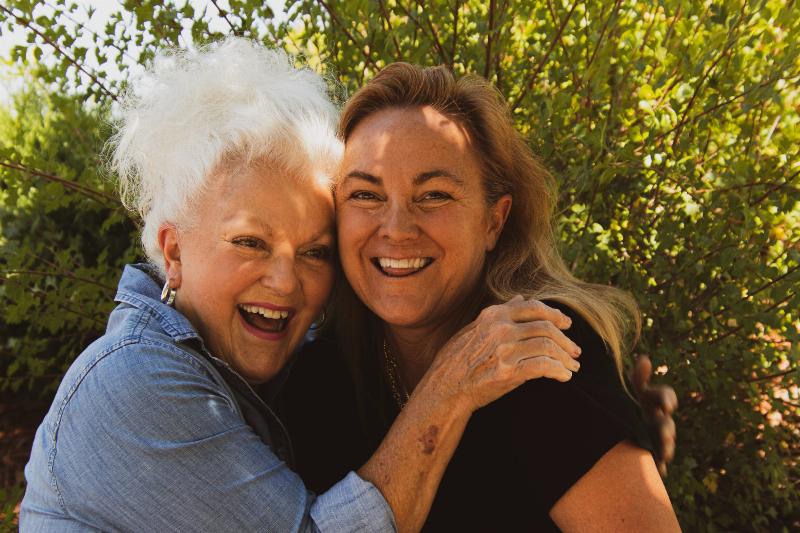 older women hug while smiling