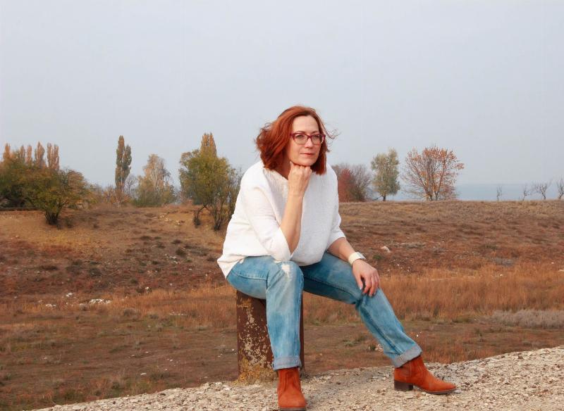 woman sits on metal and poses outdoors