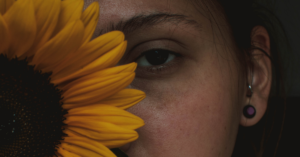 woman hiding behind sunflower
