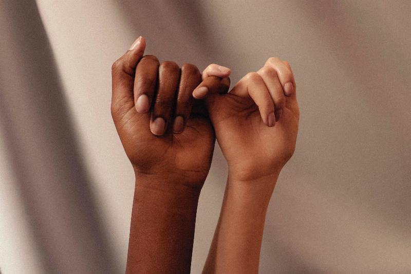 two hands of different skin tones link fingers