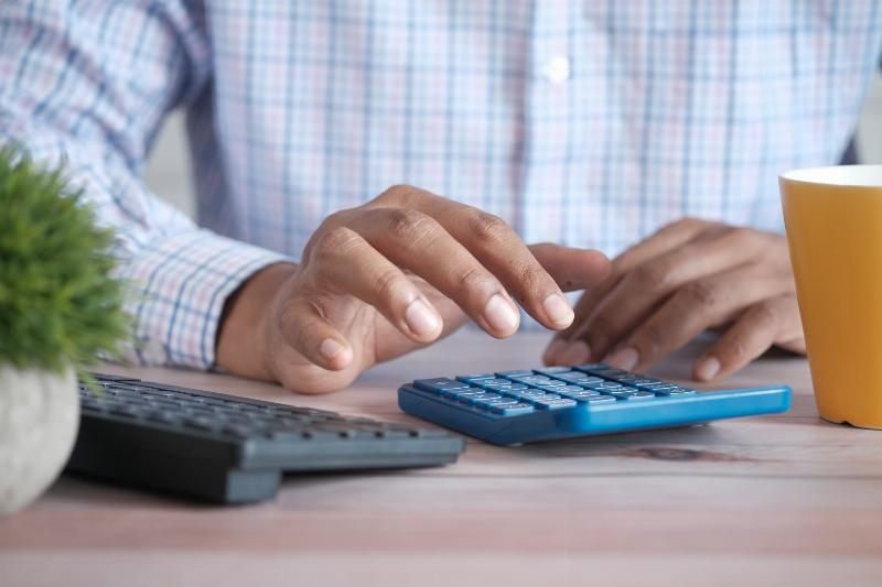 man using two calculators at his desk