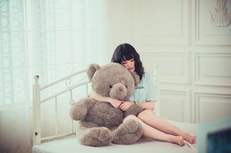 woman hugs giant teddy bear on bed
