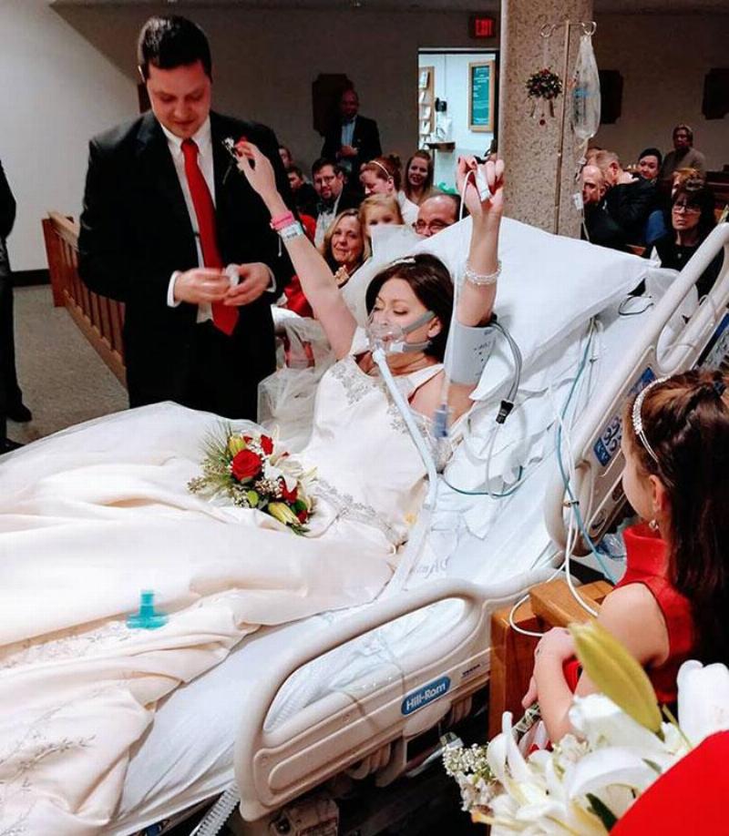 bride puts her hands up in celebration while on hospital bed