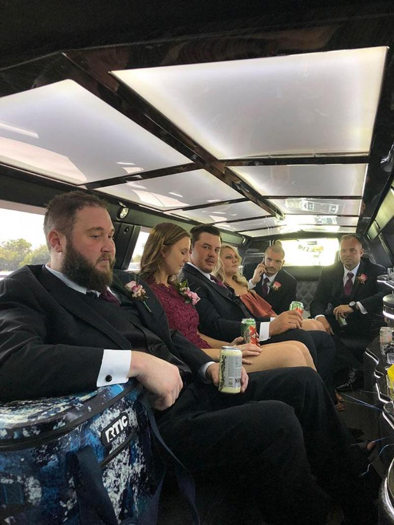 bridal party sits in limo with drinks in their hands