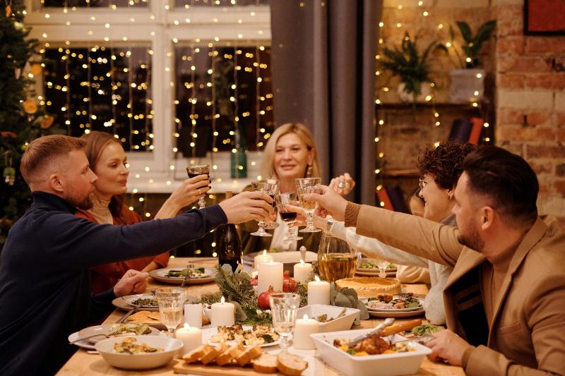 family sits around dinner table and cheer their wine