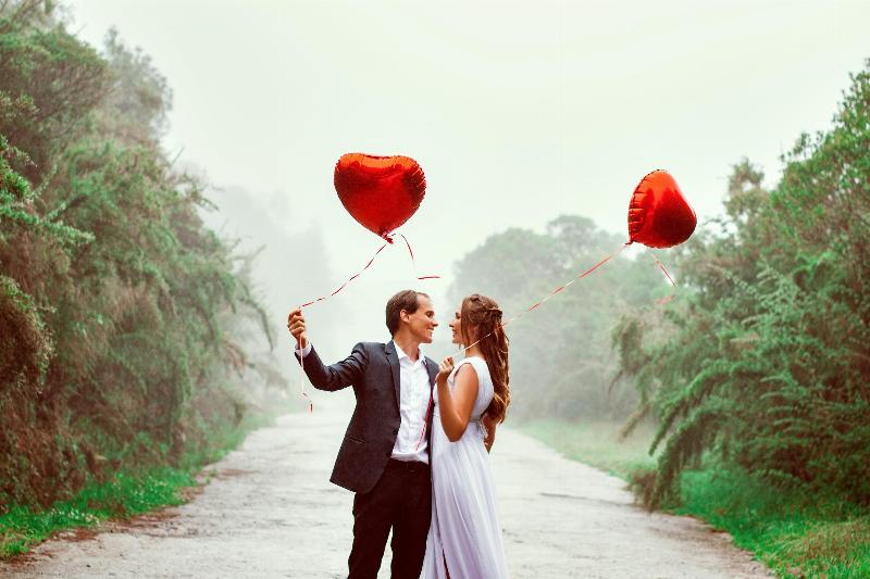 man and woman holding heart shaped balloons