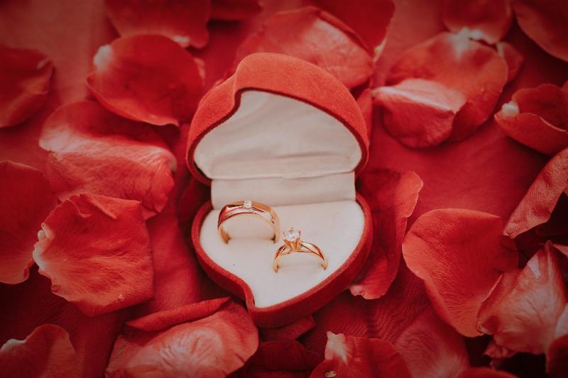 engagement ring in heart shaped box over petals