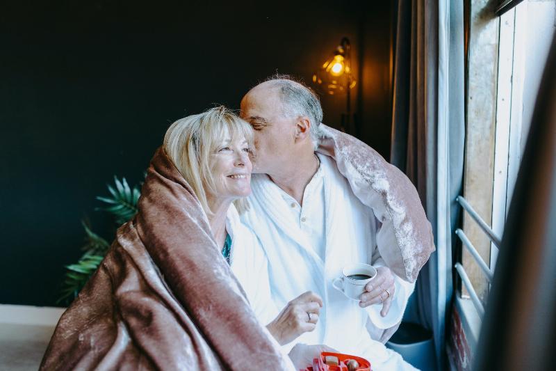 older man kissing woman on the cheek while wrapped in blanket