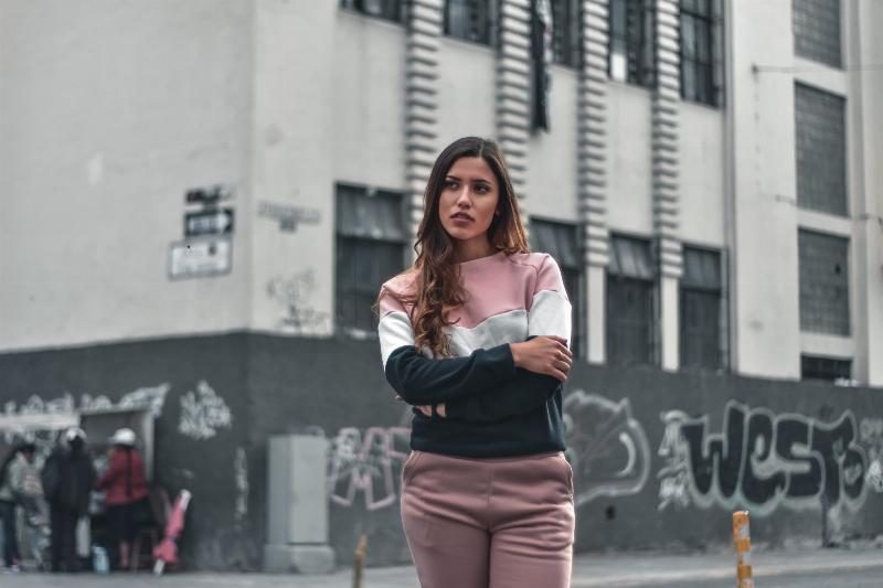 woman stands on street with arms crossed