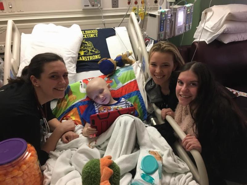 nolan surrounded by visitors and treats in hospital bed