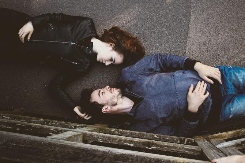 couple lays down on the floor in opposite directions and looks at each other