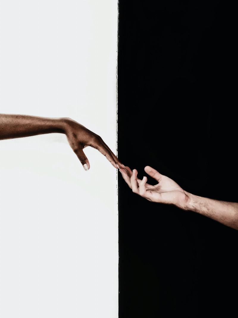 hands touching one another over black and white split background