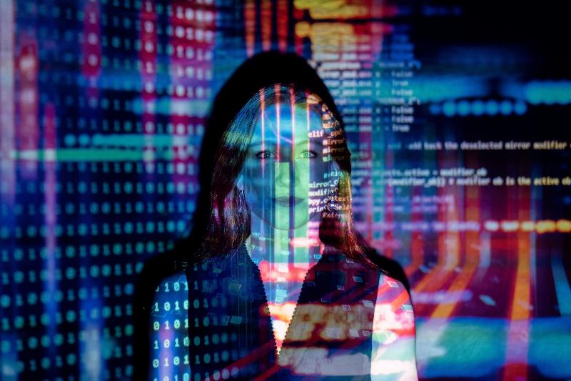 woman standing in reflection of colorful artificial projection of a computer screen