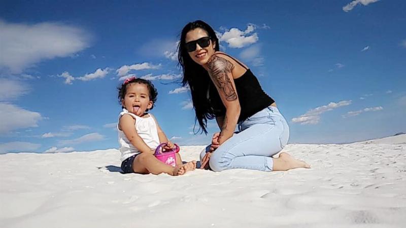 Young Faviola at the beach with her mother smiling at the camera