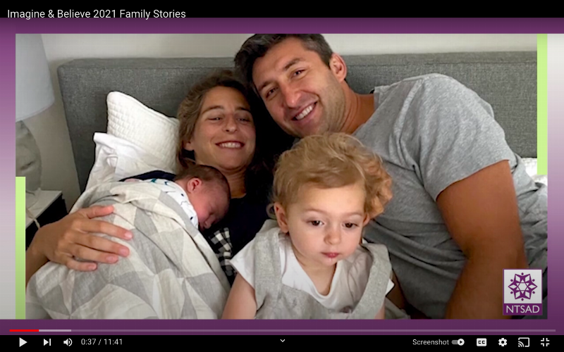 family smiles in bed with their babies