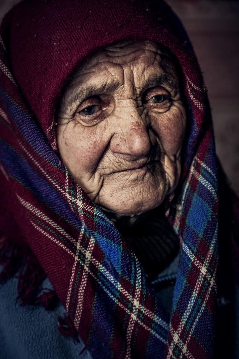 old lady wrapped in a scarf looks sad or tied