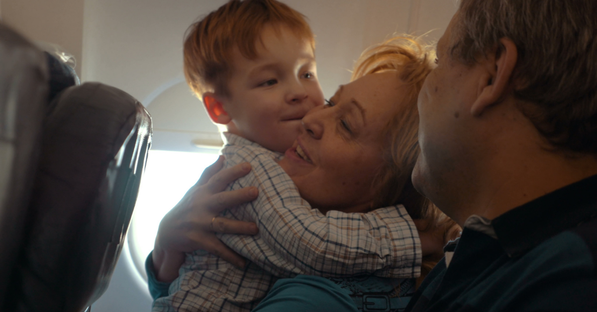 Grandma hugs grandchild on plane