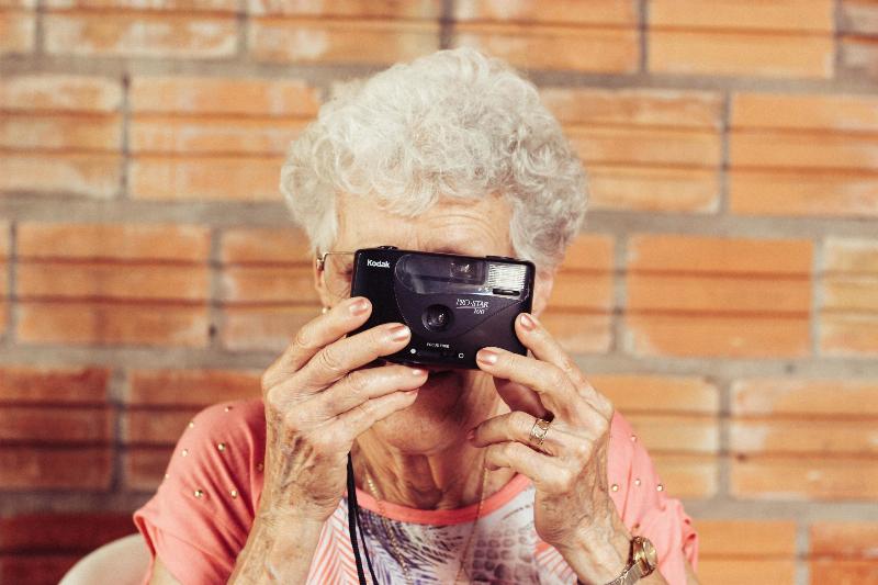 Grandma holds Kodak camera up to her eye