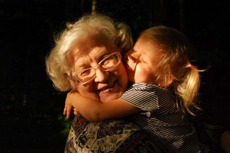 Grandma holds grandaughter close and smiles as they hug