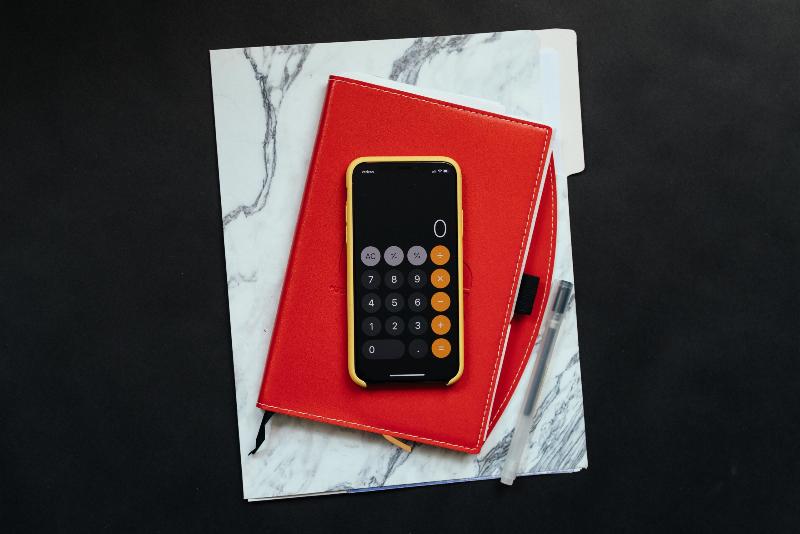iphone calculator on top of red agenda and notebook
