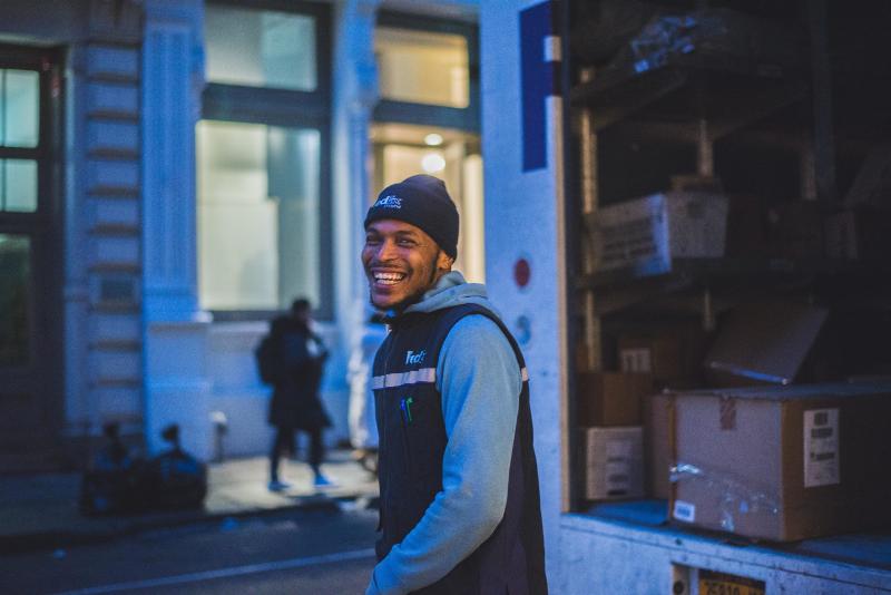 fedex employee standing by truck and smiling